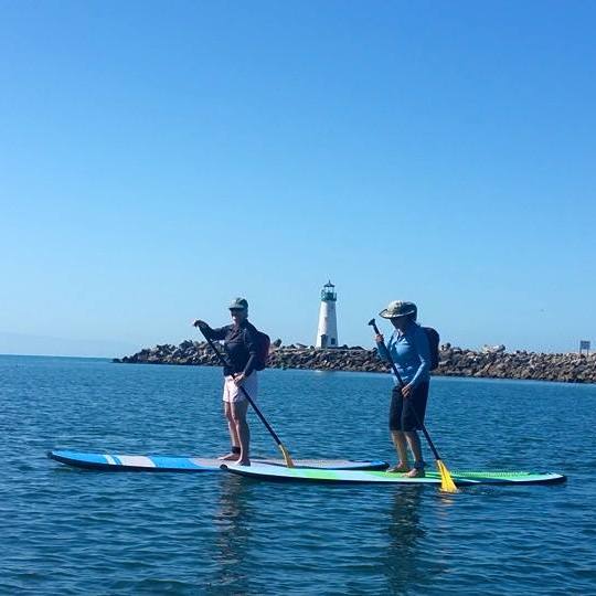 two people paddleboard in the harbor