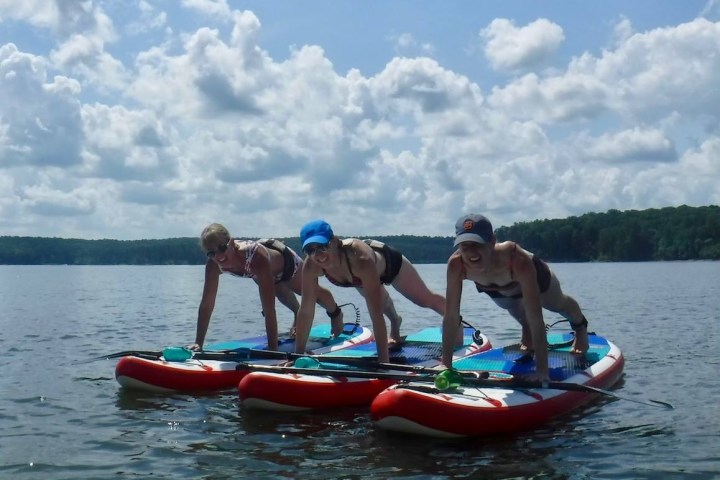 Three people doing yoga on paddleboards on a lake.