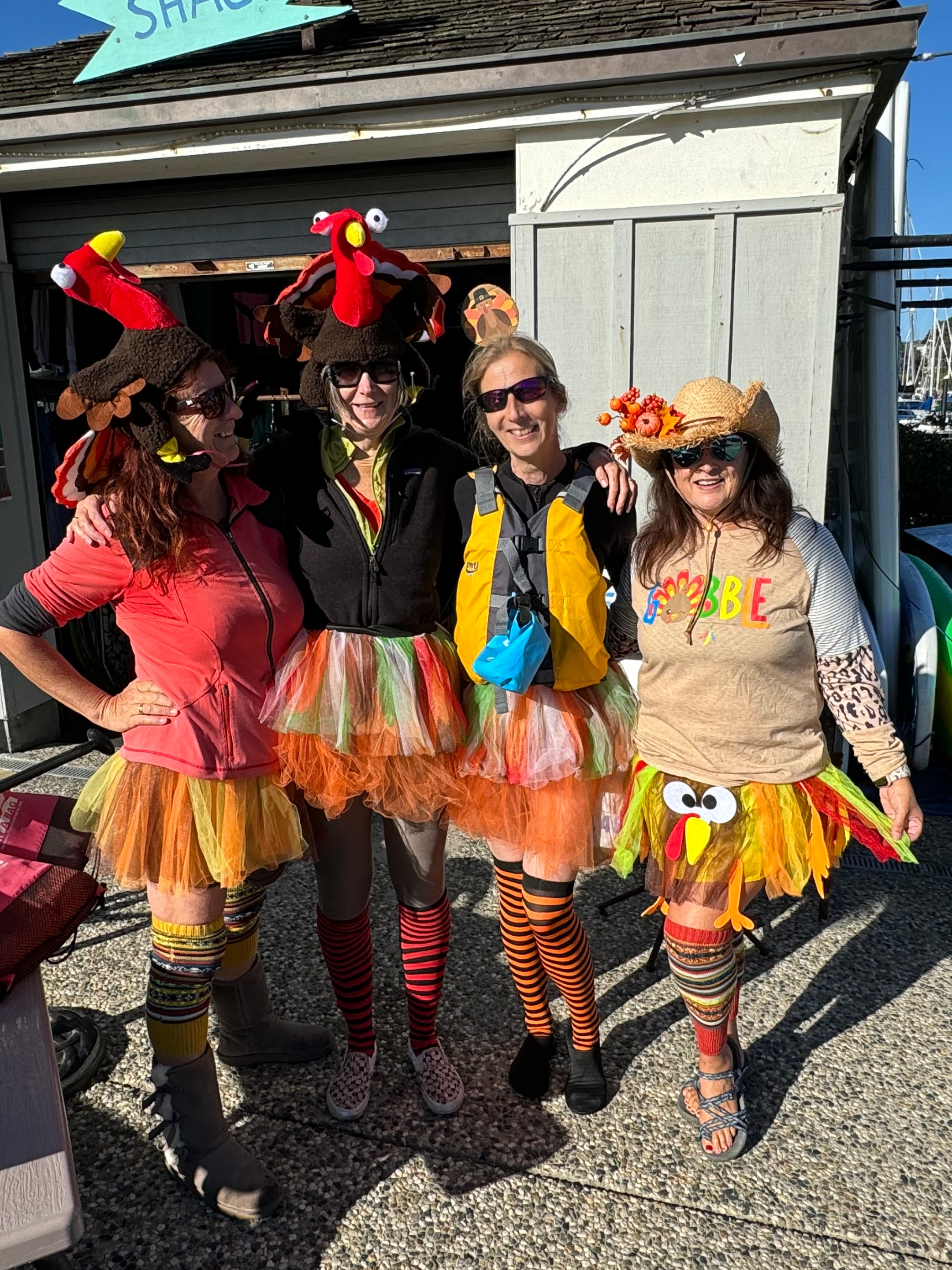 Four people in turkey-themed costumes standing in front of a shed.