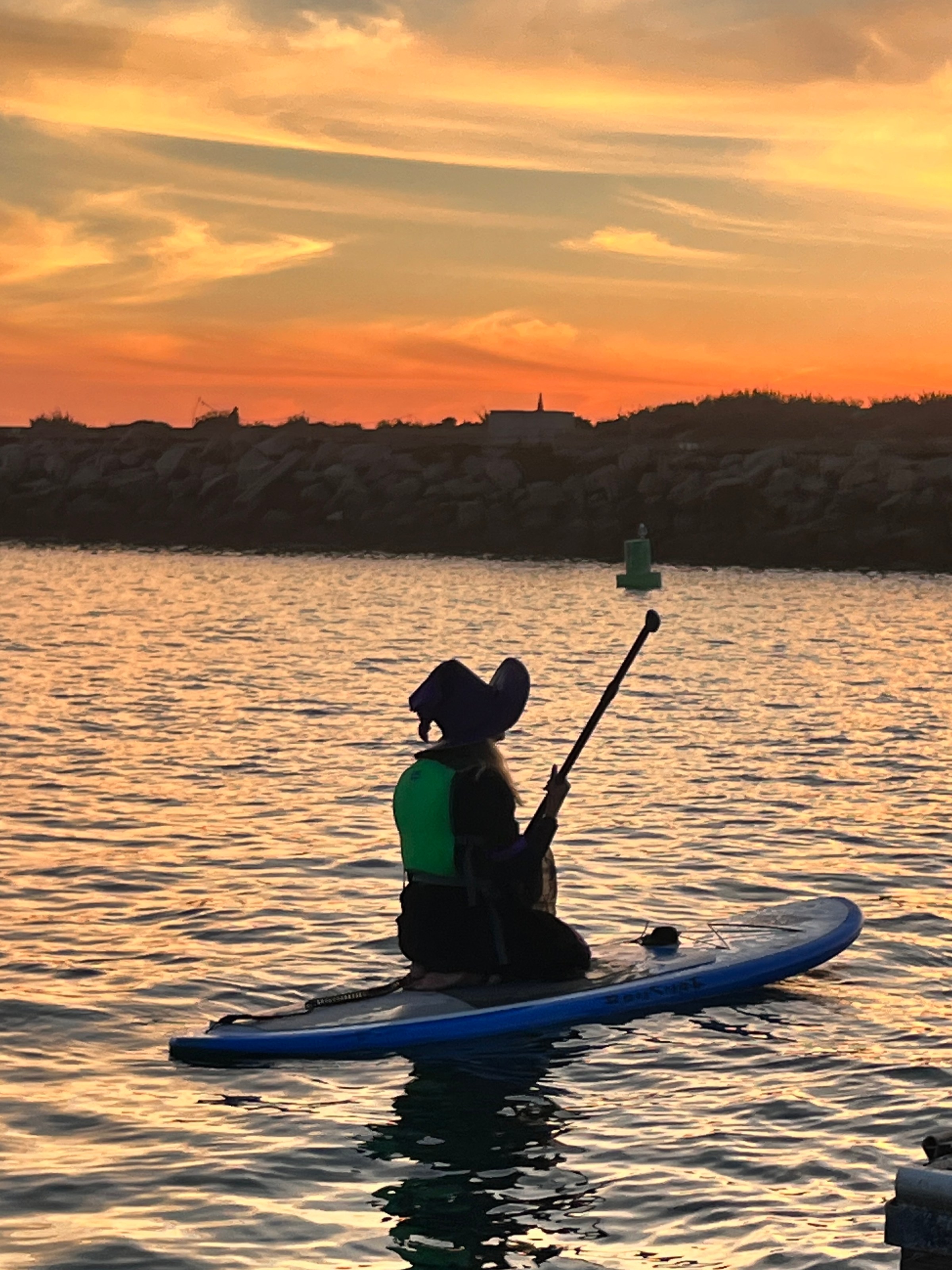 Person paddleboarding on water during sunset.
